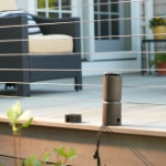 A Thermacell mosquito repellent device in the foreground, in the background: a family relax on a patio