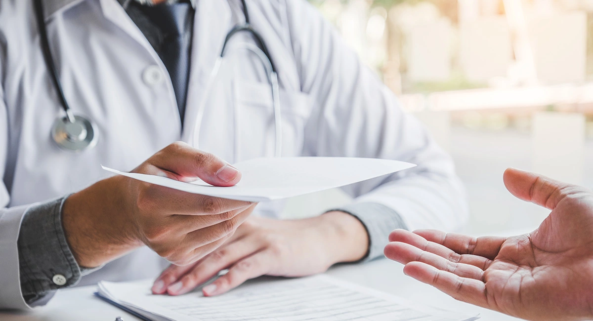 ‘A doctor hands a piece of paper to a person out of shot’