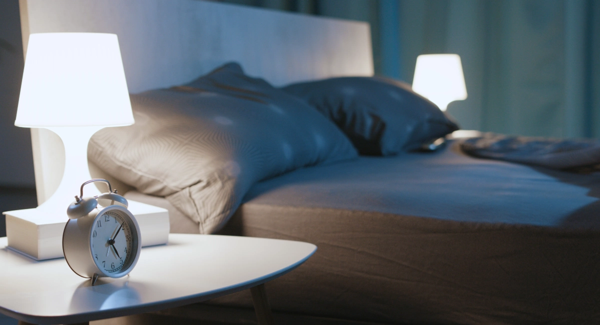 ‘An unmade bed, next to which are two bedside lamps.’