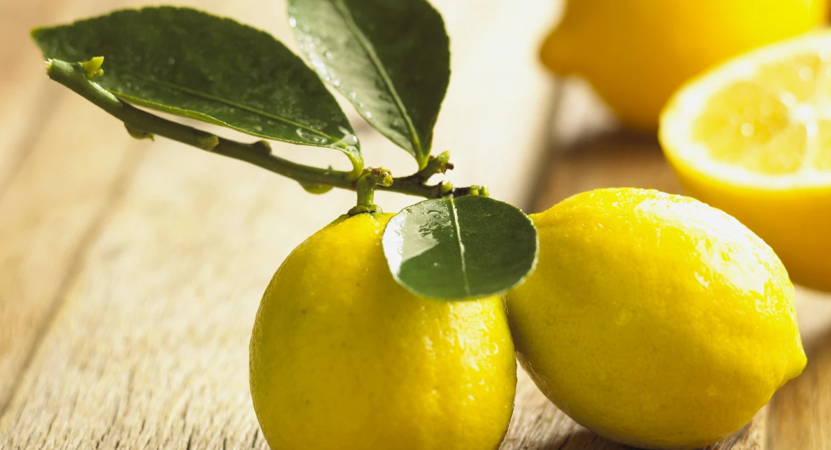 A bunch of lemons sit on a wooden countertop