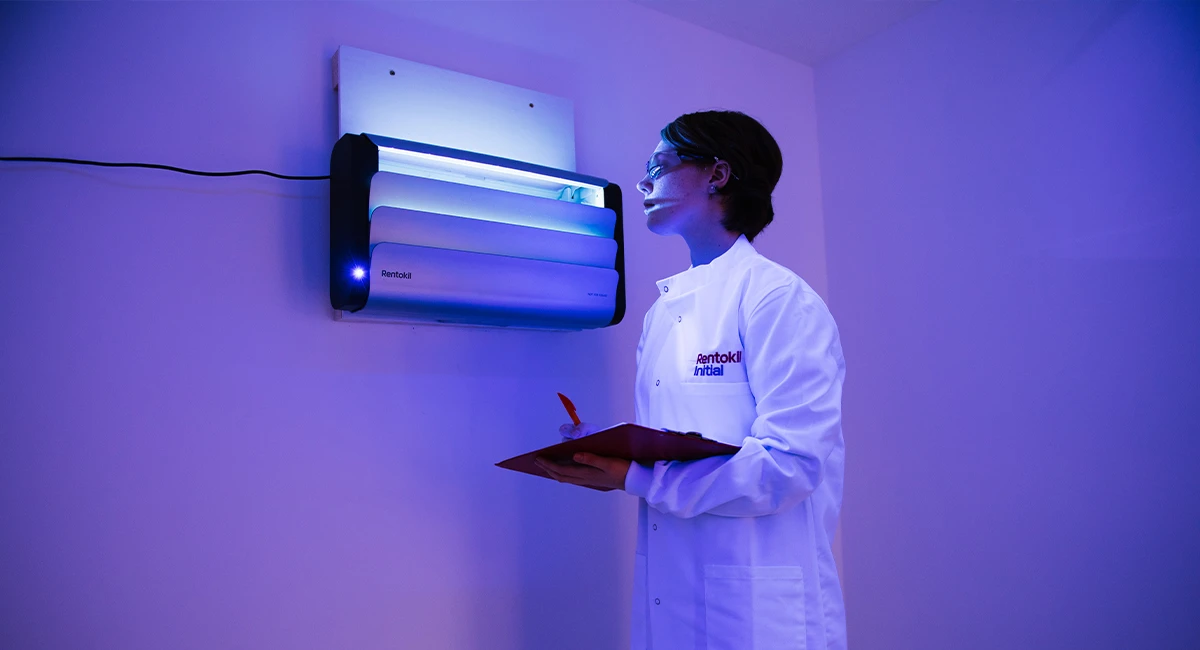 A technician in a white coat with a clipboard observing the Lumnia Standard insect light trap