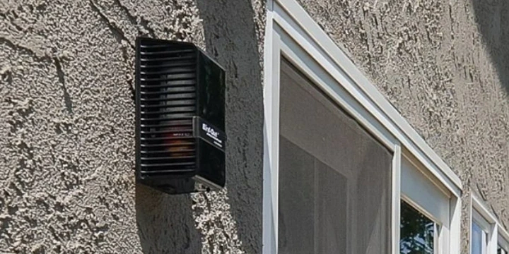 Black Bird-Out wall dispenser attached to the side of a house by a screen door. 