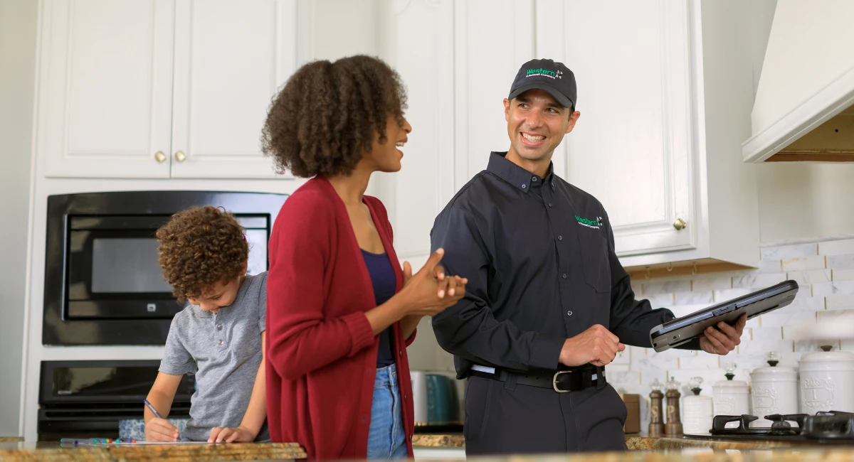 western exterminator technician talking to a customer 