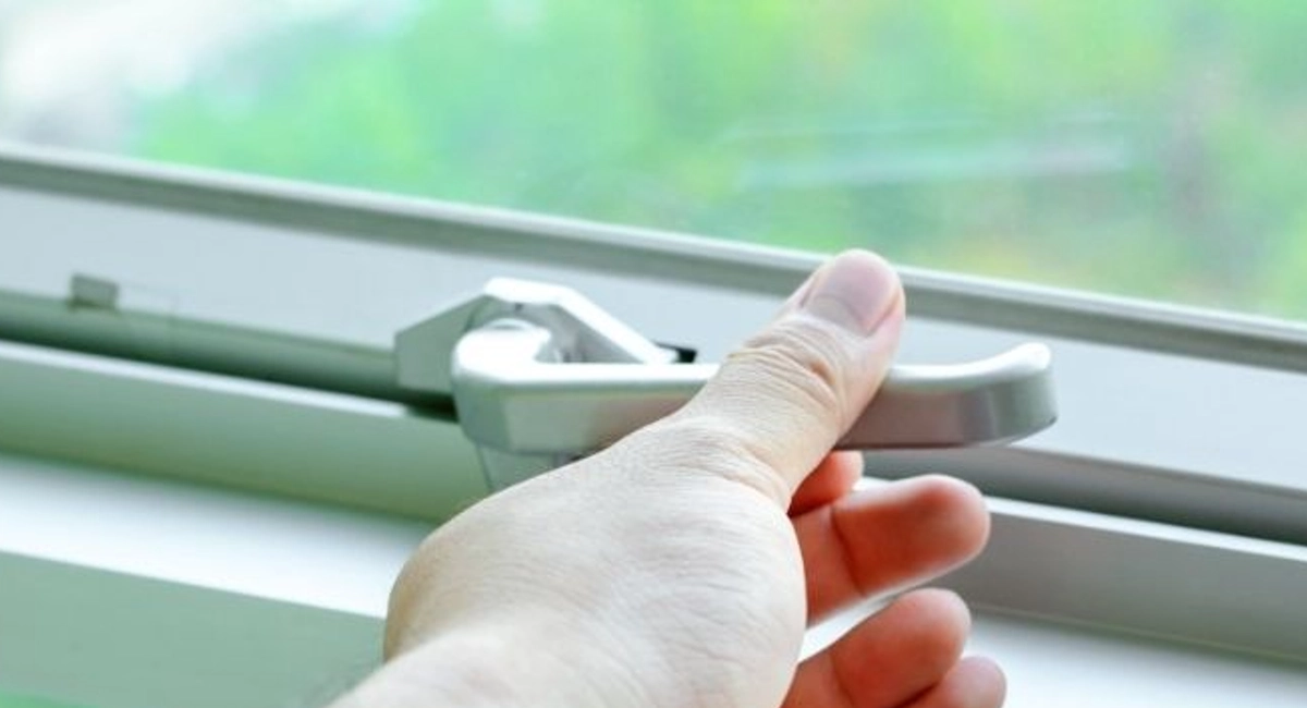 Close up of a man's hand locking a glass window.