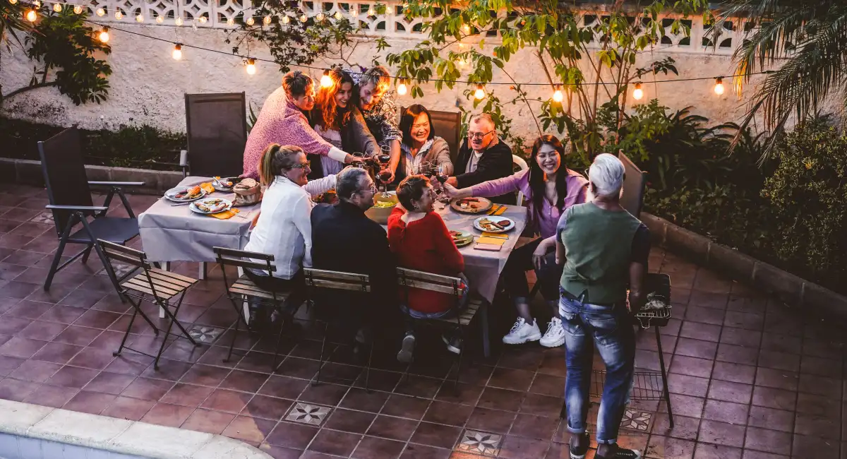 Happy family eating and cheering with red wine at barbecue party dinner
