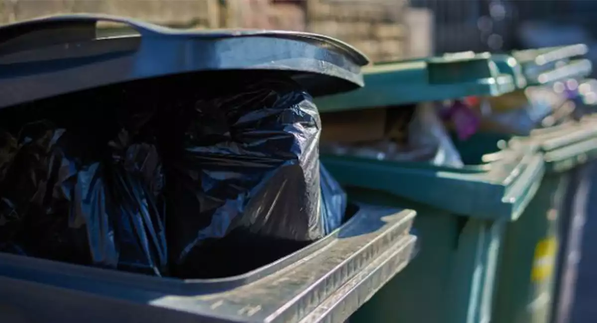 Gray and green garbage cans overfilled with trash